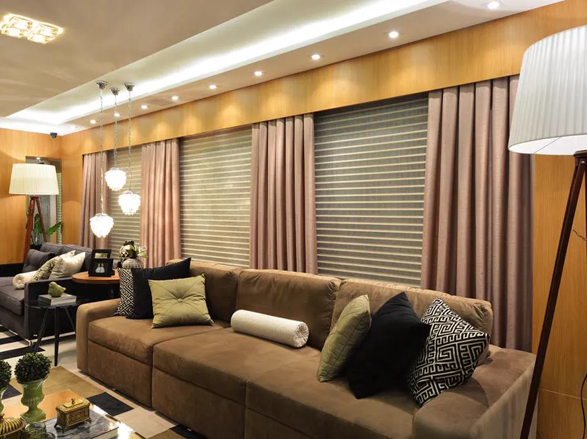 Sala de estar com cortinas e persianas na parede de janelas.