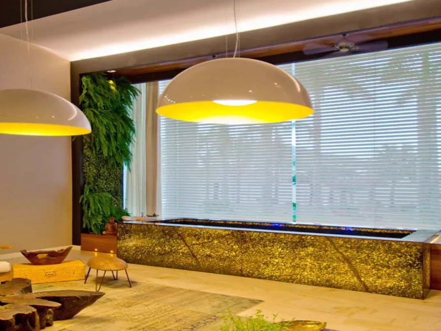 Sala com persianas horizontais, jardim vertical e luminárias pendentes.
