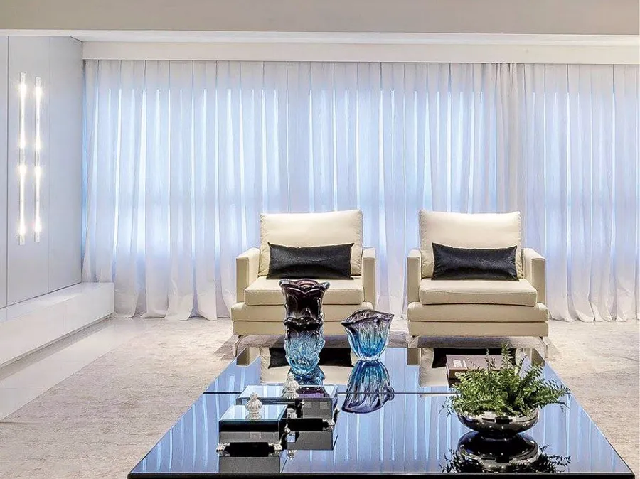 Sala de estar com cortinas de voil branco do teto ao piso.